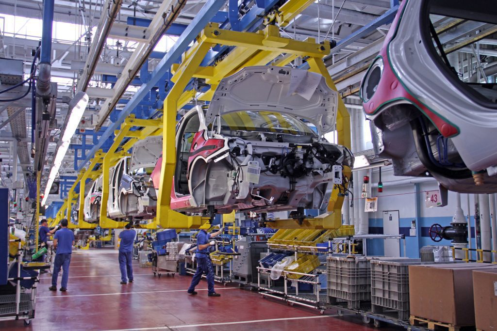 Manufacturing workers using high tech machines at an automotive plant