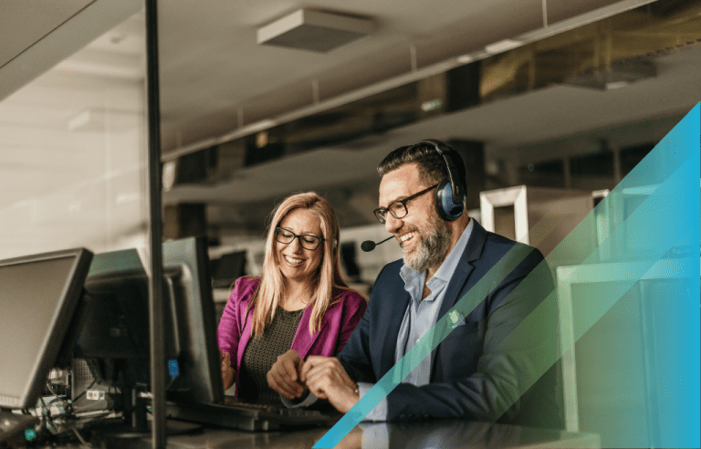 Two IT consultants on computers wearing headsets smiling.