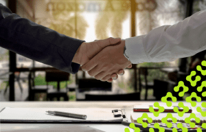 Close up of a handshake, and a pen laying on paperwork on a clipboard.