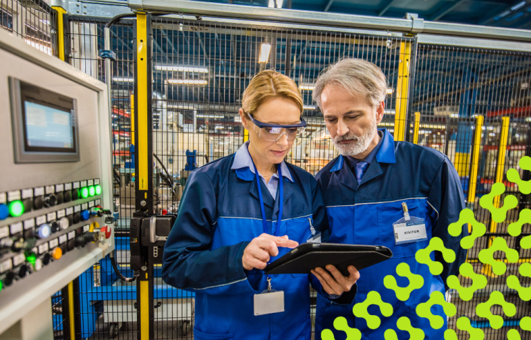 Man and woman looking and pointing at a tablet while standing in a control room in a factory.