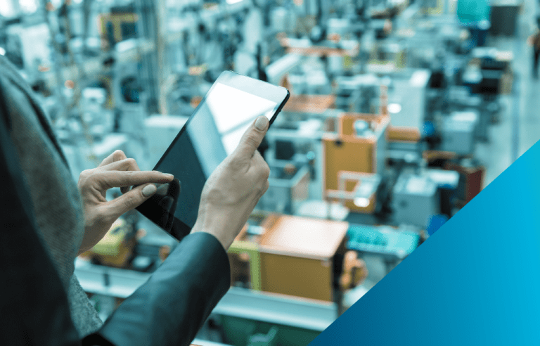 Close up of a woman's hands on a tablet overseeing a factory.