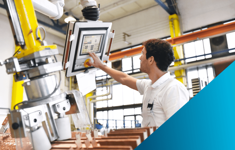 A male operator in a white shirt is interacting with a HMI touchscreen mounted on a yellow industrial machine in a brightly lit factory.