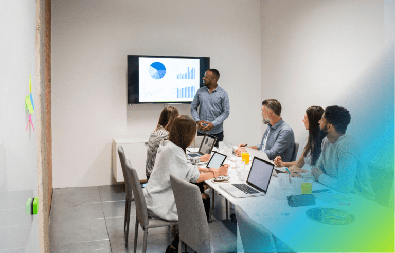A small group of professionals in a meeting room, focused on a presentation of analytics.