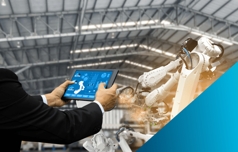 A person in a suit is holding a tablet that displays industrial data, with white robotic arms working in the background of a large factory.
