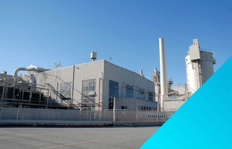A large industrial building with a smokestack under a clear sky.