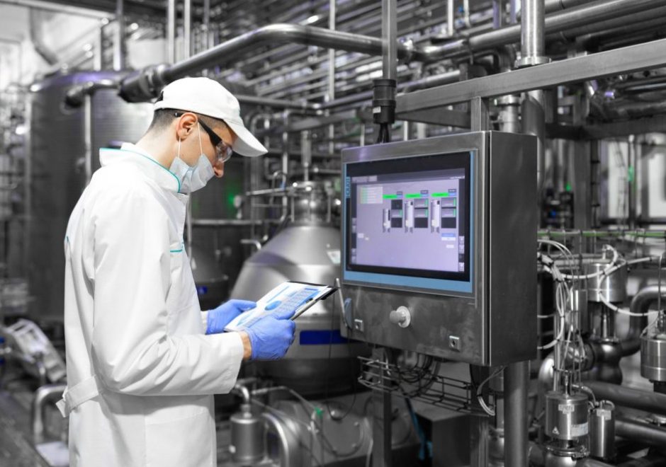 Man wearing protective gear and a mask while monitoring manufacturing processes at a plant