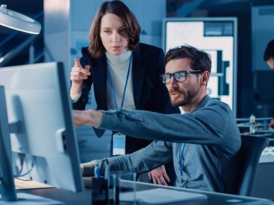 Man and woman discussing solutions in front of a computer in business environment